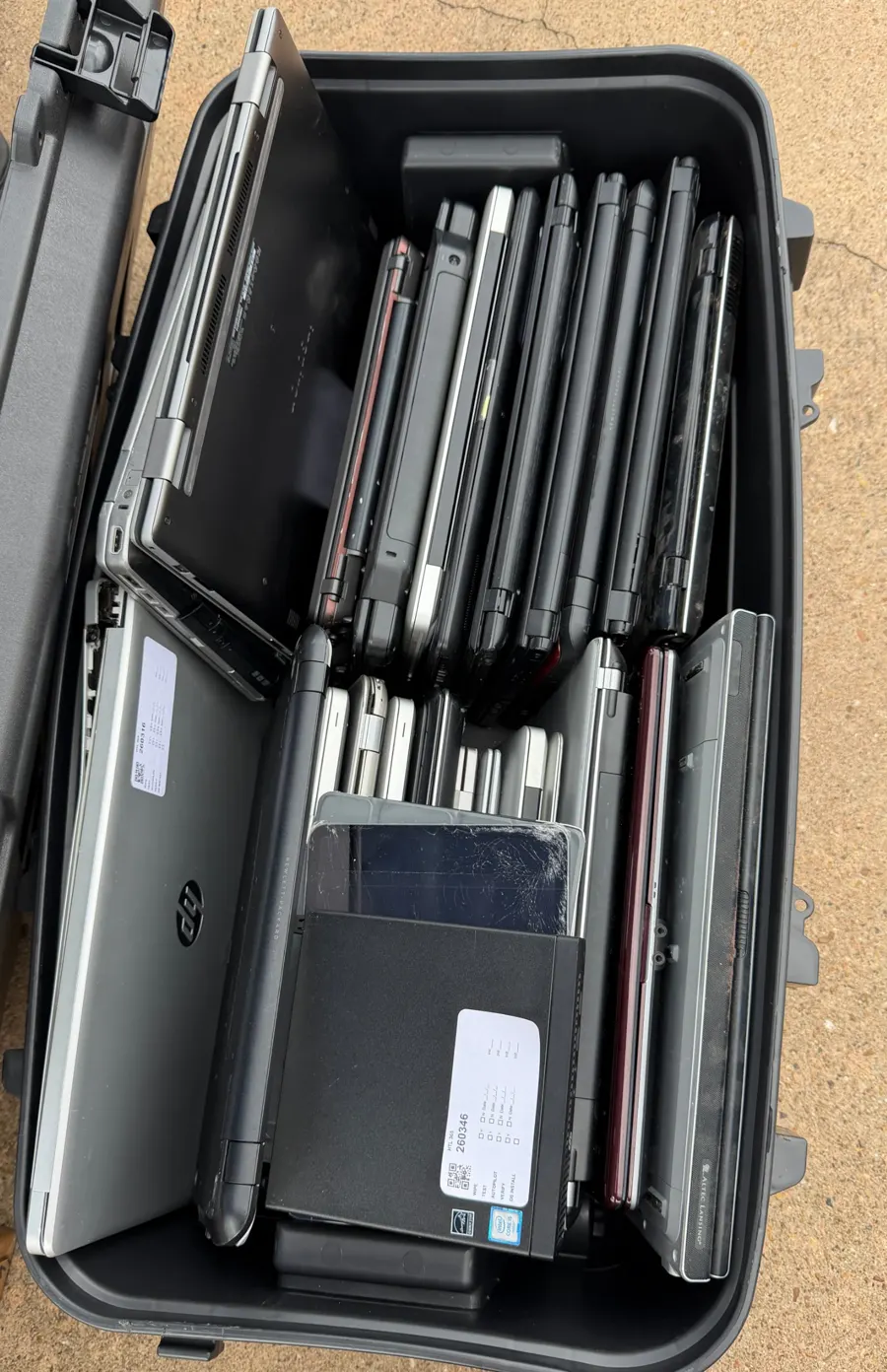 Bin of collected laptops, each tagged with an HTL 365 asset label